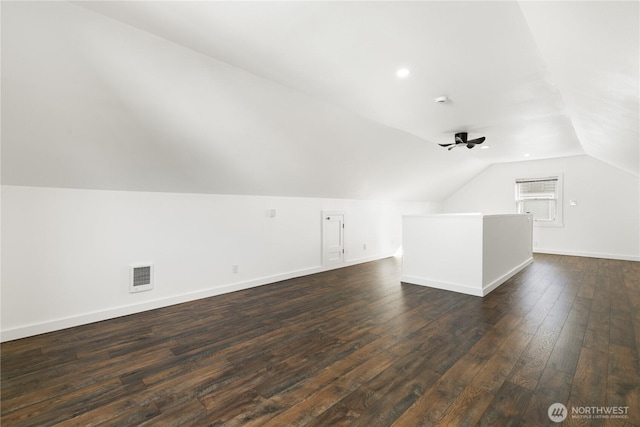 additional living space featuring visible vents, dark wood-type flooring, ceiling fan, baseboards, and lofted ceiling