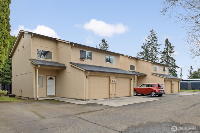 townhome / multi-family property with driveway, a shingled roof, and a garage