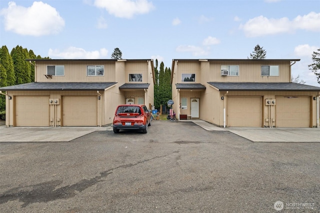 view of property featuring cooling unit, driveway, a garage, and roof with shingles