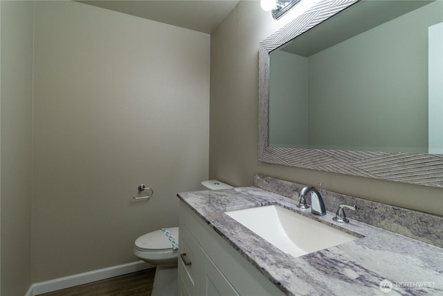 bathroom featuring vanity, toilet, wood finished floors, and baseboards