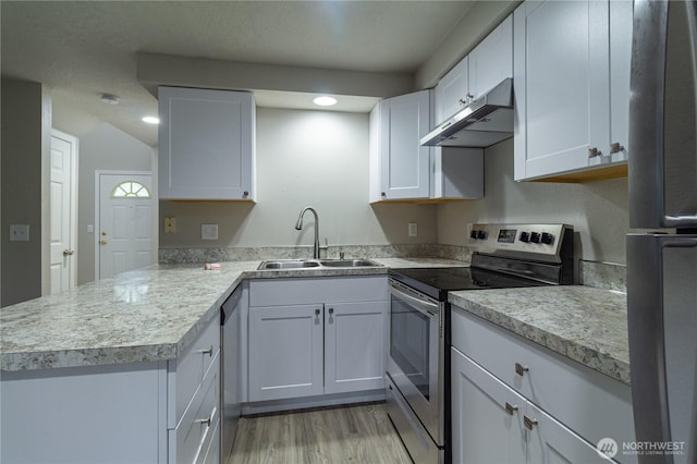 kitchen with under cabinet range hood, appliances with stainless steel finishes, light countertops, and a sink