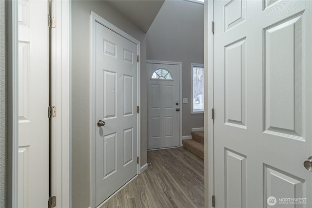 foyer featuring baseboards, wood finished floors, and stairs