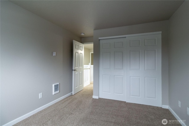 unfurnished bedroom with a closet, visible vents, baseboards, and carpet