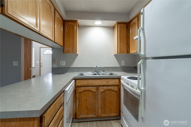 kitchen featuring brown cabinets, white appliances, a peninsula, and a sink