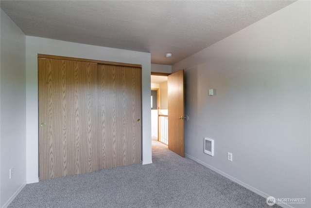 unfurnished bedroom featuring visible vents, a textured ceiling, a closet, carpet, and baseboards