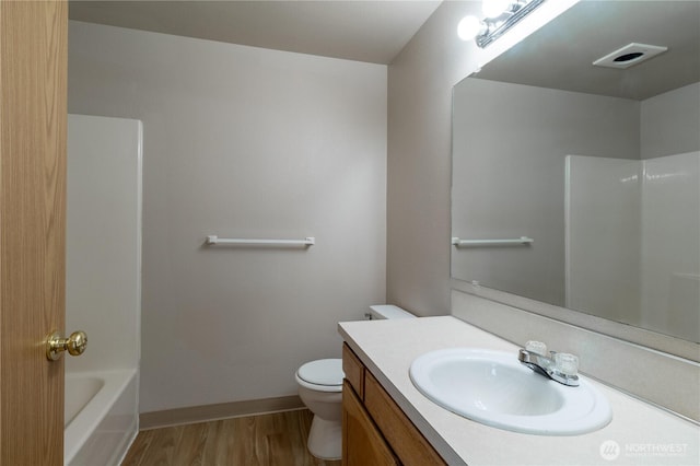 bathroom featuring vanity, wood finished floors, visible vents, toilet, and a washtub