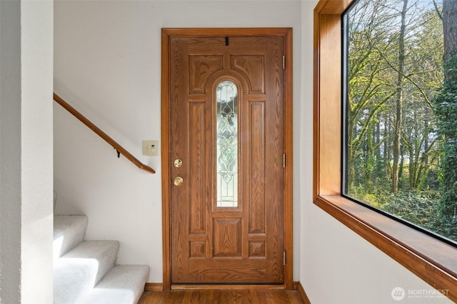 foyer entrance with stairs, baseboards, and wood finished floors