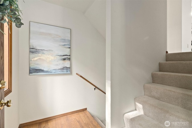 staircase with baseboards, lofted ceiling, and wood finished floors