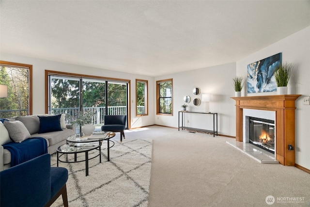 carpeted living room with baseboards and a glass covered fireplace