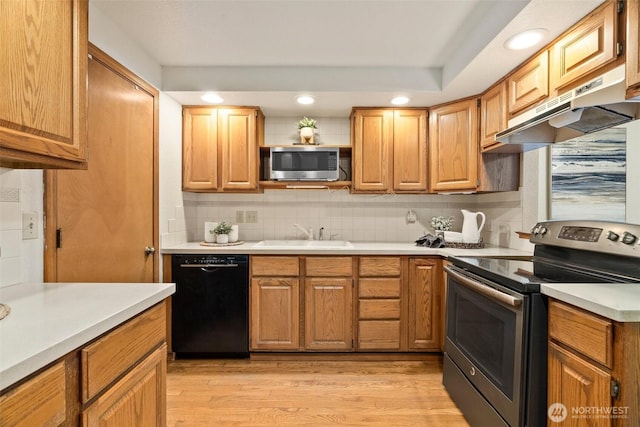 kitchen featuring under cabinet range hood, backsplash, stainless steel appliances, and a sink