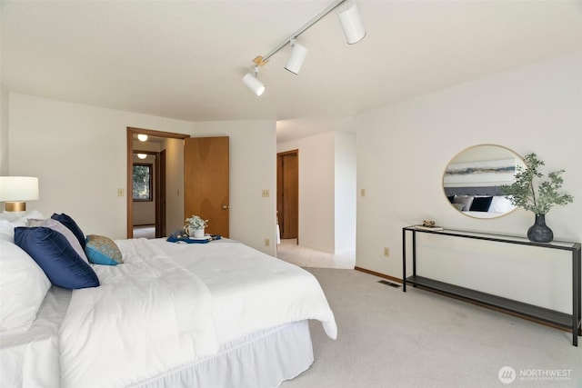 bedroom featuring light carpet, visible vents, and track lighting