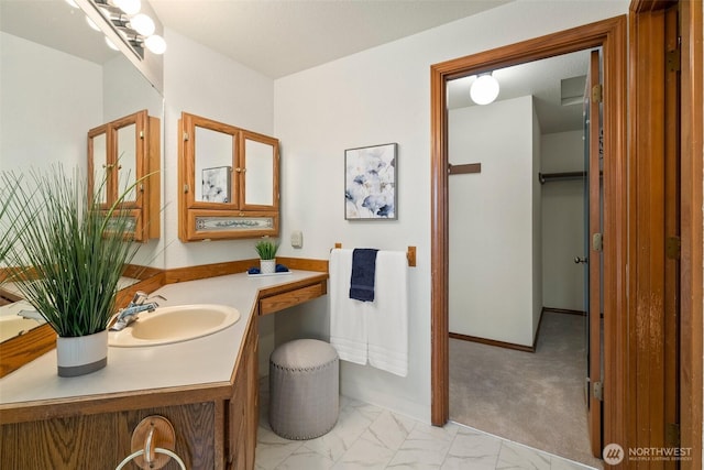 bathroom featuring baseboards, marble finish floor, and vanity