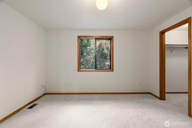 unfurnished bedroom featuring a walk in closet, baseboards, visible vents, and carpet floors