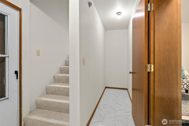 staircase with baseboards and marble finish floor