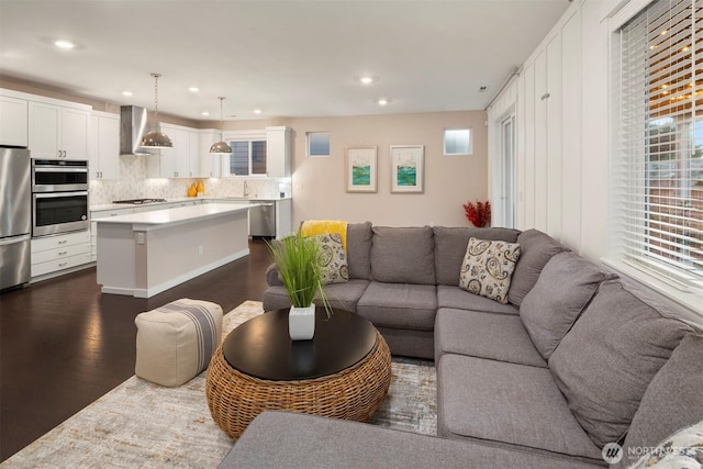 living area with dark wood-type flooring and recessed lighting