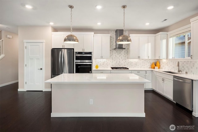 kitchen with backsplash, a kitchen island, wall chimney range hood, stainless steel appliances, and a sink