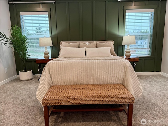 bedroom with a decorative wall, baseboards, and carpet floors