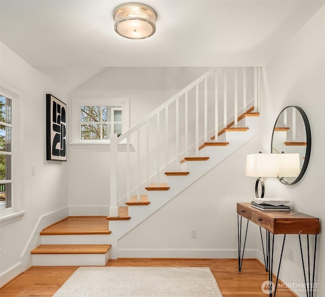 stairs featuring plenty of natural light, wood finished floors, and baseboards