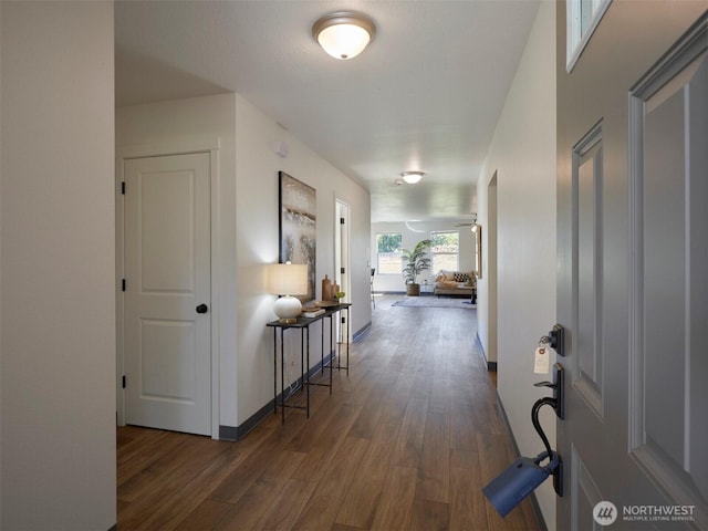 corridor featuring dark wood finished floors and baseboards