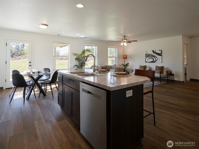 kitchen featuring stainless steel dishwasher, dark wood-type flooring, a sink, and a kitchen breakfast bar