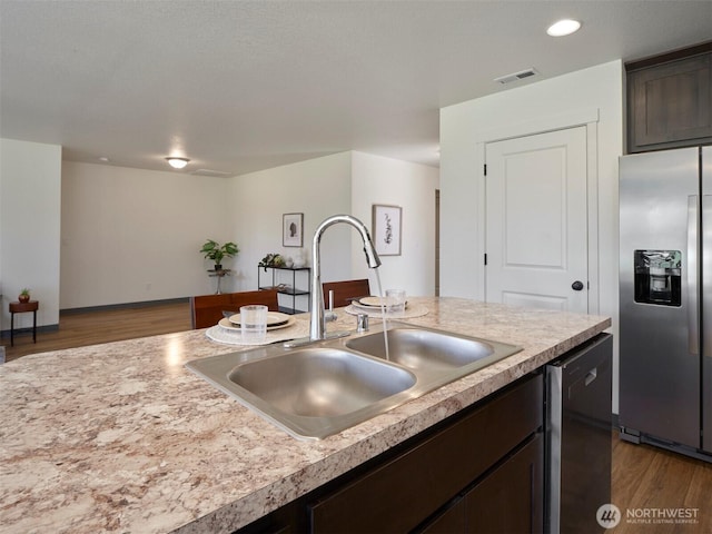 kitchen with visible vents, a sink, dark brown cabinets, stainless steel fridge, and dishwasher