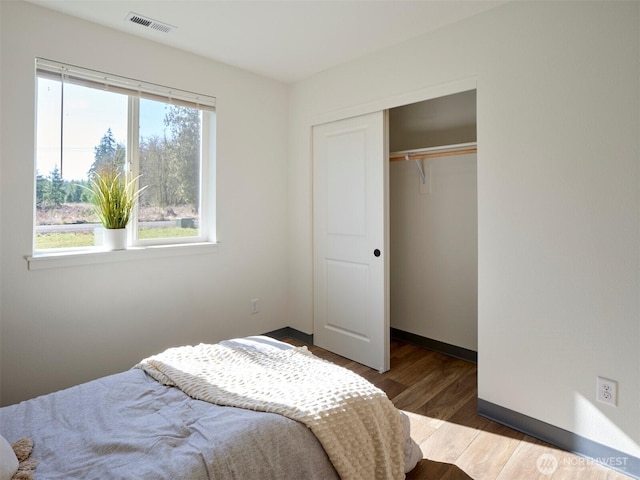 bedroom featuring a closet, multiple windows, wood finished floors, and visible vents