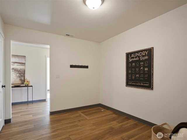 unfurnished room featuring visible vents, baseboards, and wood finished floors