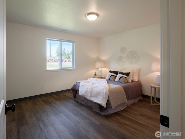 bedroom with visible vents, baseboards, and wood finished floors