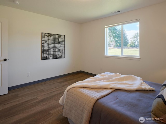 bedroom featuring baseboards, visible vents, and wood finished floors