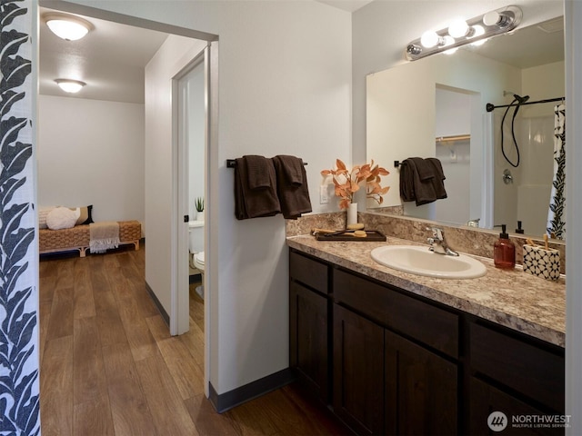 full bath featuring curtained shower, toilet, wood finished floors, vanity, and baseboards