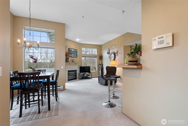 dining space with a chandelier, carpet flooring, a tile fireplace, and a baseboard radiator