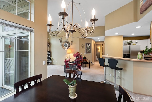 carpeted dining area with a high ceiling, recessed lighting, and a chandelier