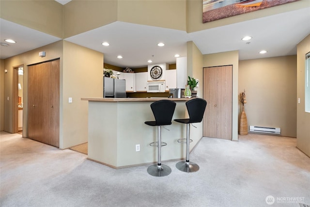 kitchen with light carpet, white microwave, baseboard heating, and freestanding refrigerator