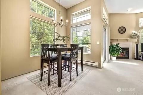 dining room featuring a baseboard heating unit, a glass covered fireplace, and a notable chandelier