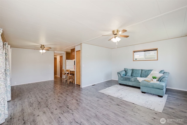 living area featuring baseboards, a ceiling fan, and wood finished floors