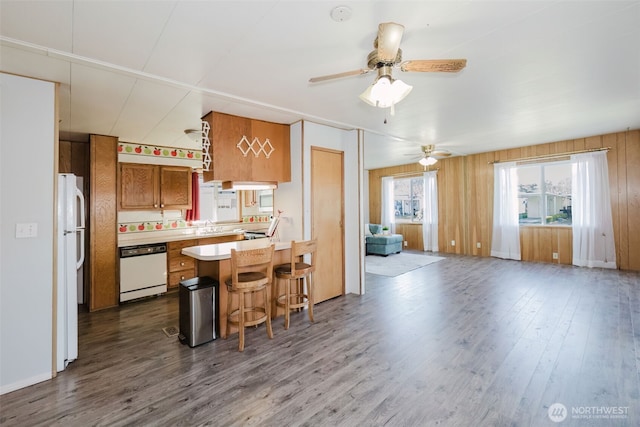 kitchen with white appliances, open floor plan, dark wood-type flooring, a peninsula, and light countertops