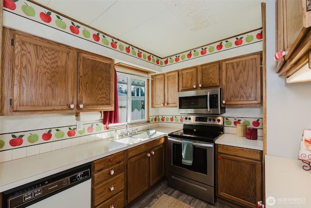 kitchen with stainless steel appliances, brown cabinets, light countertops, and a sink