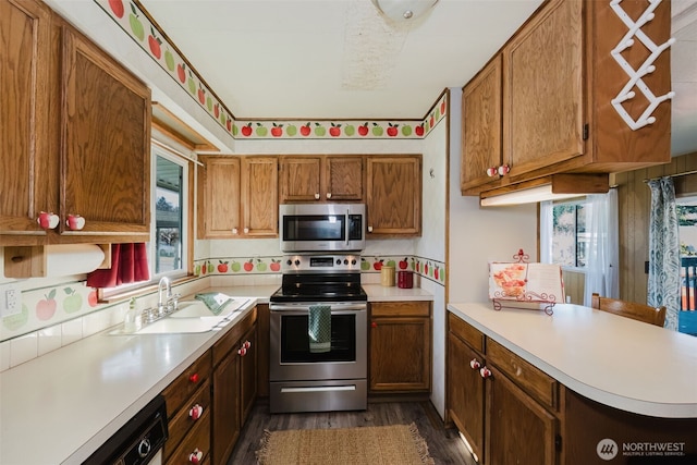 kitchen with appliances with stainless steel finishes, brown cabinets, light countertops, and a sink