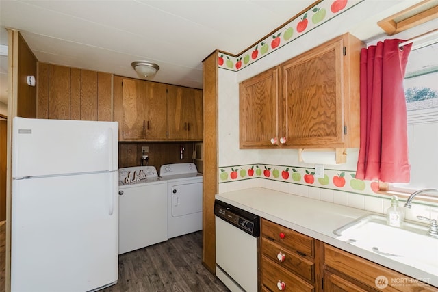 kitchen with washer and clothes dryer, light countertops, brown cabinetry, a sink, and white appliances