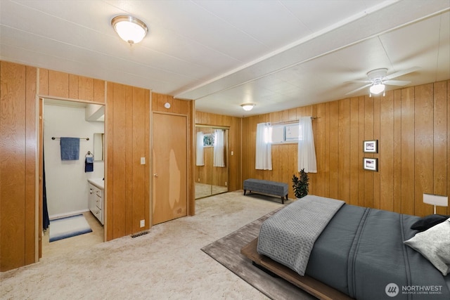 carpeted bedroom with wood walls, connected bathroom, and visible vents