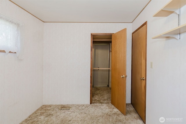 interior space with carpet flooring, visible vents, and crown molding