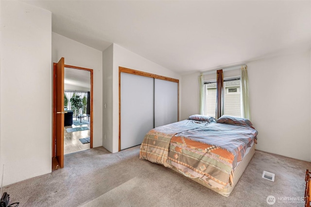 bedroom with lofted ceiling, a closet, visible vents, and multiple windows