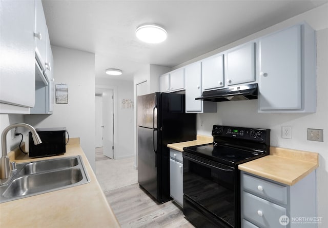 kitchen featuring light countertops, white cabinets, a sink, under cabinet range hood, and black appliances