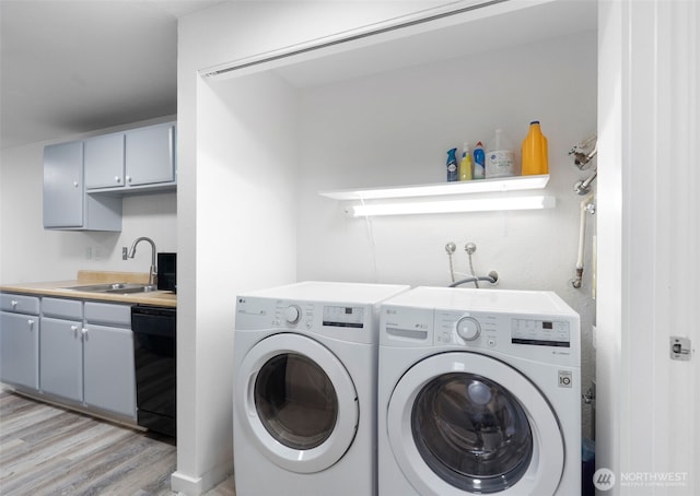 laundry room with light wood finished floors, laundry area, separate washer and dryer, and a sink