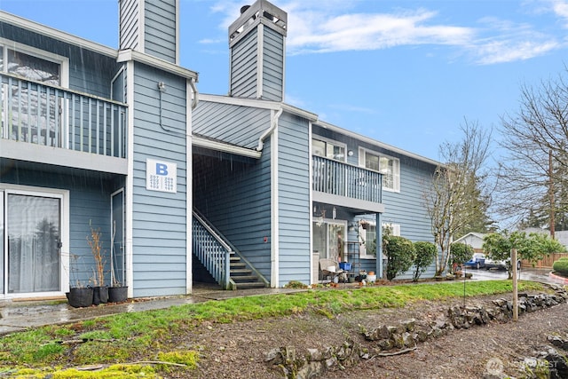 back of property featuring a chimney and stairway