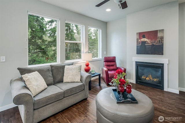 living area featuring wood finished floors, baseboards, a ceiling fan, recessed lighting, and a glass covered fireplace