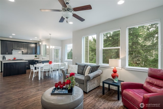 living area featuring dark wood-style floors, recessed lighting, and ceiling fan with notable chandelier