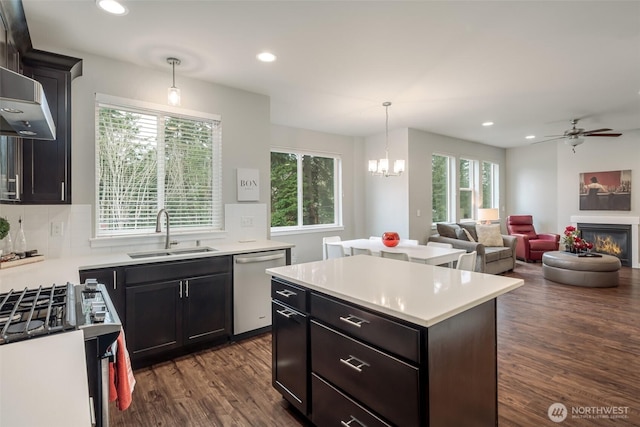 kitchen featuring a glass covered fireplace, a kitchen island, a sink, light countertops, and stainless steel dishwasher