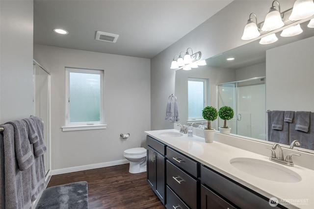 full bathroom with a sink, visible vents, wood finished floors, and a shower stall