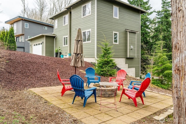 back of house with a patio area, an attached garage, and a fire pit